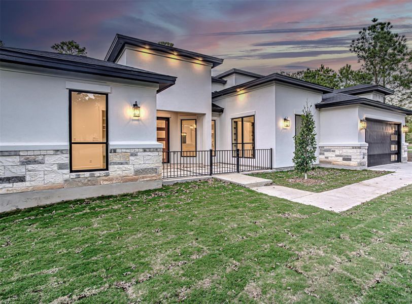 Modern home with stone siding, a lawn, a garage, and stucco siding Modern home with stone siding, a lawn, a garage, and stucco siding