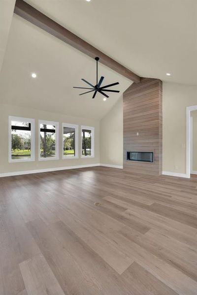 Unfurnished living room with light wood-type flooring, a fireplace, and beamed ceiling