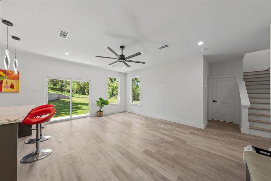 Unfurnished living room with stairway, visible vents, light wood-type flooring, and a healthy amount of sunlight