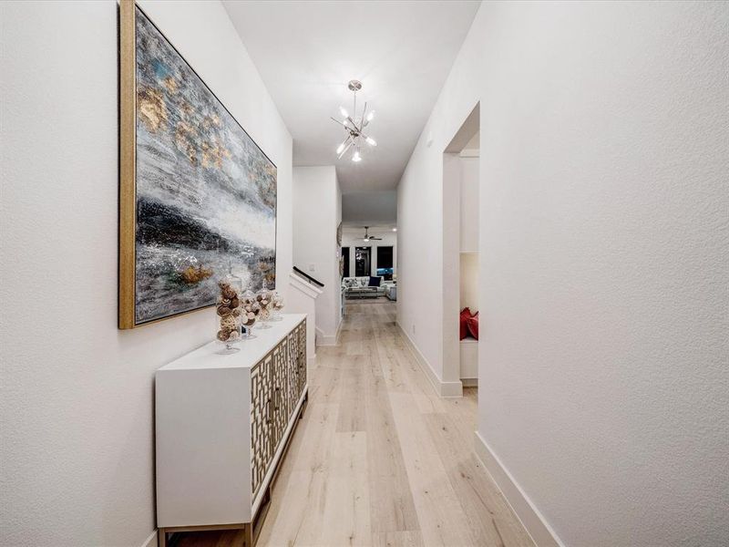 Corridor featuring light wood-type flooring and a chandelier Corridor featuring light wood-type flooring and a chandelier