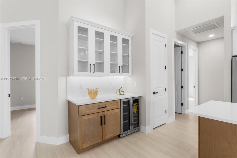 Built-in BUTLER'S PANTRY w/ quartz countertop, glass-front cabinetry, warm wood base cabinets & WINE REFRIGERATOR, ideal for BEVERAGE STATION, COFFEE BAR, or EXTRA STORAGE & PREP SPACE. Built-in BUTLER'S PANTRY w/ quartz countertop, glass-front cabinetry, warm wood base cabinets & WINE REFRIGERATOR, ideal for BEVERAGE STATION, COFFEE BAR, or EXTRA STORAGE & PREP SPACE.