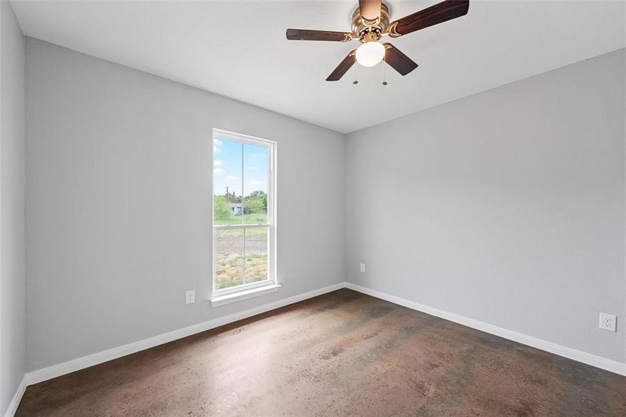Spare room with concrete flooring, ceiling fan, and baseboards