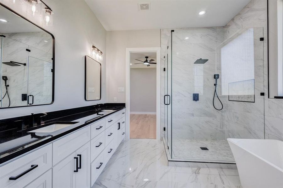 Bathroom featuring a double vanity with white cabinetry and black countertops, dual rectangular sinks, and matte black hardware