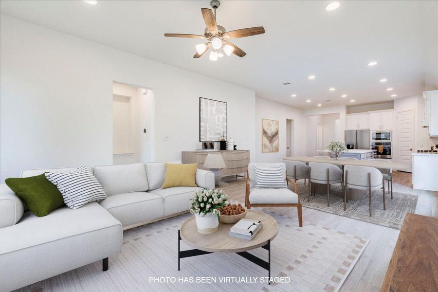 This open-concept interior features a ceiling fan, recessed lighting, and light-toned flooring