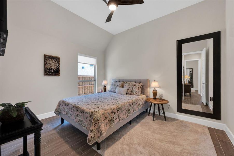 Spacious secondary bedroom with walk in closet, ceiling fan, wood look tile flooring in a neutral color scheme at 13' x 11'