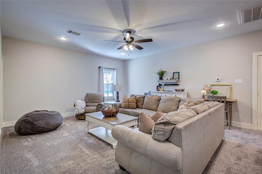 Carpeted living room featuring ceiling fan