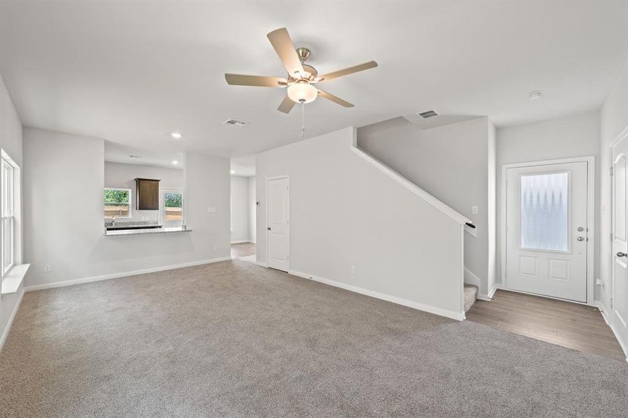 Unfurnished living room with carpet and ceiling fan