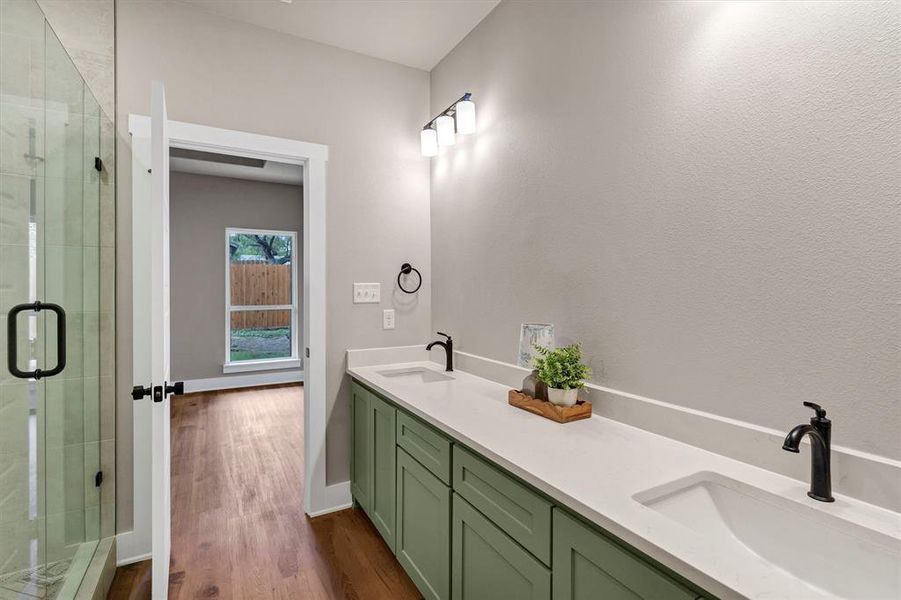 Bathroom featuring double vanity, a stall shower, and dark wood-style floors Bathroom featuring double vanity, a stall shower, and dark wood-style floors