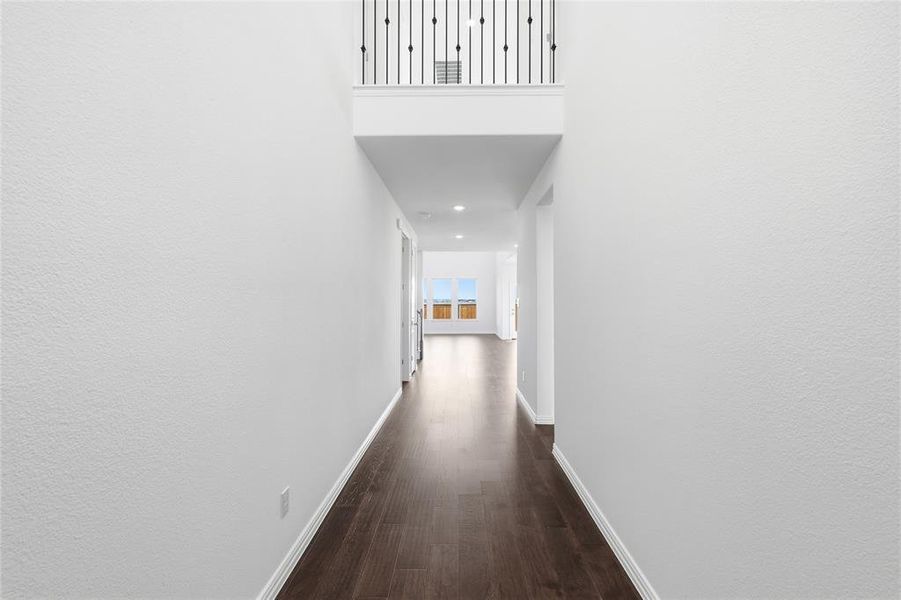 Entryway featuring dark wood-finish flooring, white baseboards, and a second-story landing with wrought iron balusters