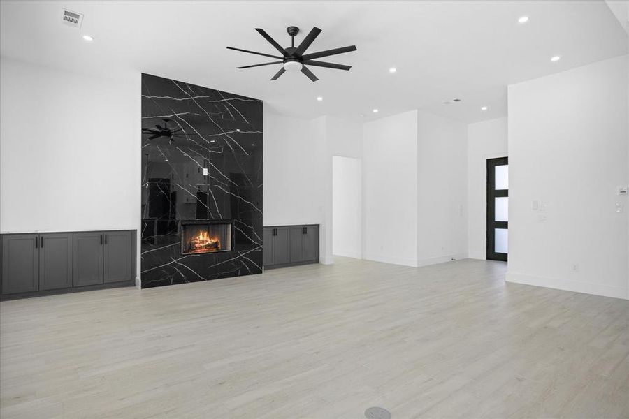 Spacious living area featuring a dramatic black and white veined fireplace, light Wood looking grey Porcelain Tile-finish flooring, recessed lighting, and a modern ceiling fan
