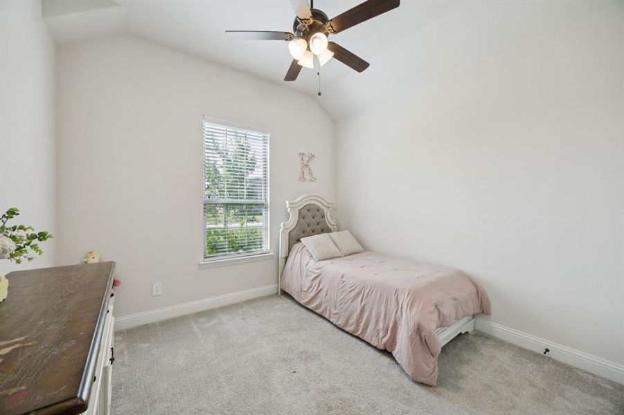 Secondary bedroom featuring lofted ceiling, carpet, and a ceiling fan.