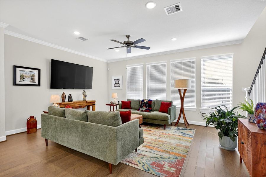 Inviting living room highlighted by wide-plank wood flooring, crown molding, and a wall of windows offering ample natural light. Inviting living room highlighted by wide-plank wood flooring, crown molding, and a wall of windows offering ample natural light.