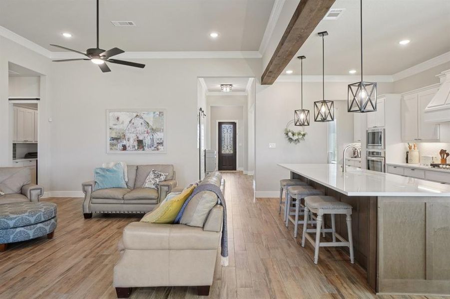 Living area with ornamental molding, light wood-look ceramic tyle flooring, recessed lighting, and ceiling fan