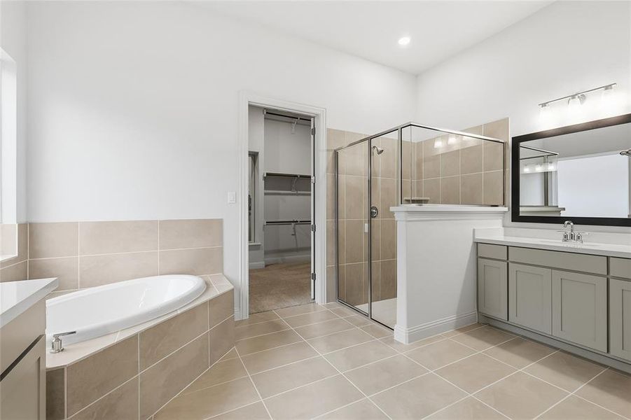 Bathroom featuring vanity, a shower stall, a garden tub, light tile patterned flooring, and a walk in closet