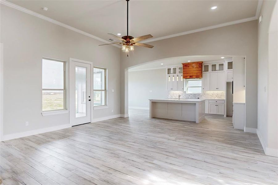 Kitchen featuring white cabinetry, light hardwood / wood-style floors, ornamental molding, and a center island