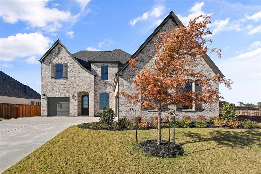 French provincial home featuring driveway, brick siding, and an attached garage