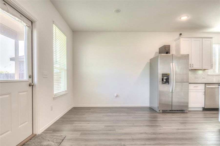 Kitchen with appliances with stainless steel finishes, white cabinets, light wood-style flooring, backsplash, and recessed lighting Kitchen with appliances with stainless steel finishes, white cabinets, light wood-style flooring, backsplash, and recessed lighting