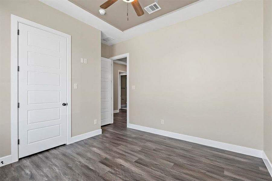 Unfurnished room with a raised ceiling, ceiling fan, and dark hardwood / wood-style floors