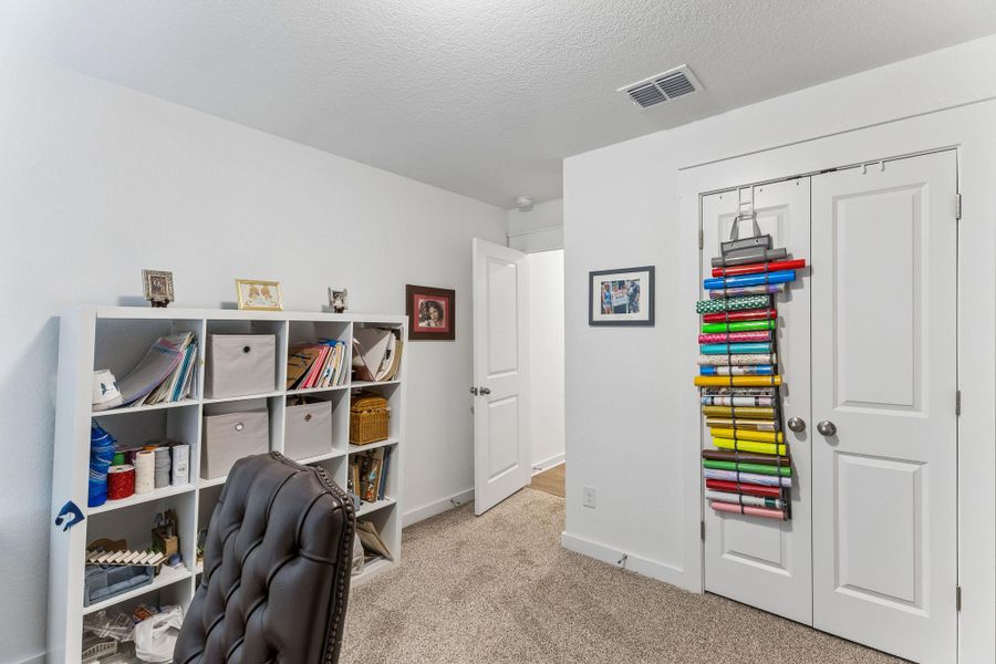 Carpeted room featuring white walls and a white built-in shelving unit