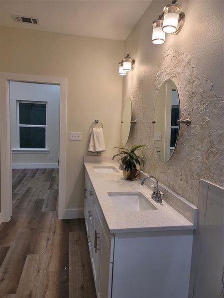 Bathroom double vanity sinks, textured paint, quartz countertop, and designer lightning.