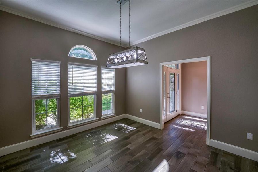 Dining area with ornamental molding, wood tile flooring, and a notable chandelier