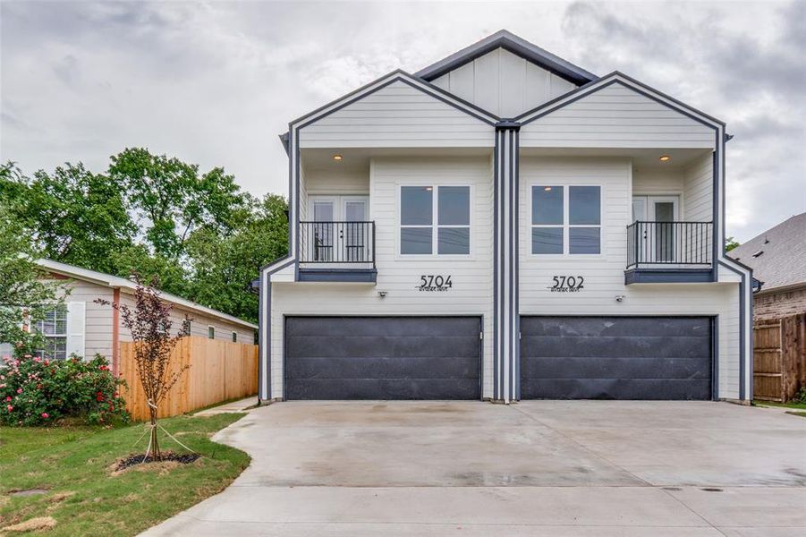 View of front facade featuring fence, driveway, a balcony, and a garage View of front facade featuring fence, driveway, a balcony, and a garage