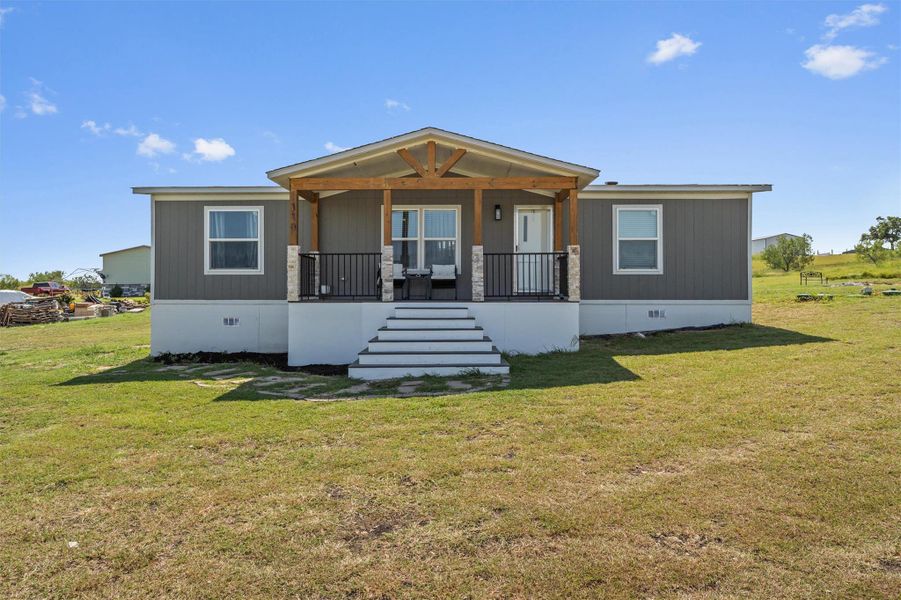 Manufactured / mobile home with crawl space, a porch, a front yard, and stairs