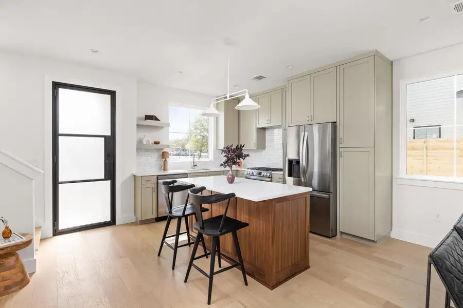 Two tone kitchen with stainless steel appliances, a center island, light wood-type flooring, a breakfast bar, and decorative backsplash