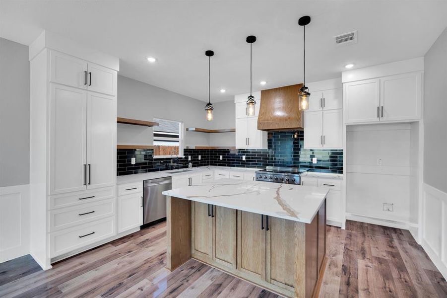 Kitchen featuring wainscoted walls, custom stove vent and decorative lighting with color-changing bulbs.