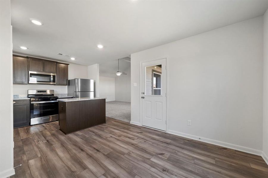 Kitchen with ceiling fan, stainless steel appliances, dark brown cabinetry, dark hardwood / wood-style flooring, and a kitchen island