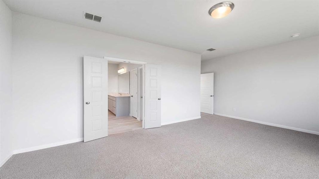 Unfurnished bedroom with ensuite bathroom and light colored carpet