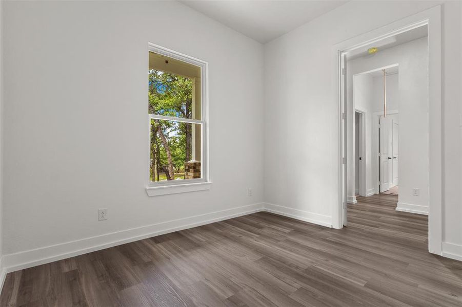 The room features sleek, dark wood-style flooring and bright white walls