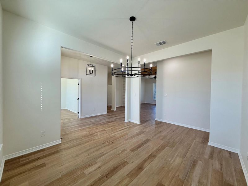 Unfurnished dining area with light wood-type flooring and hanging lights