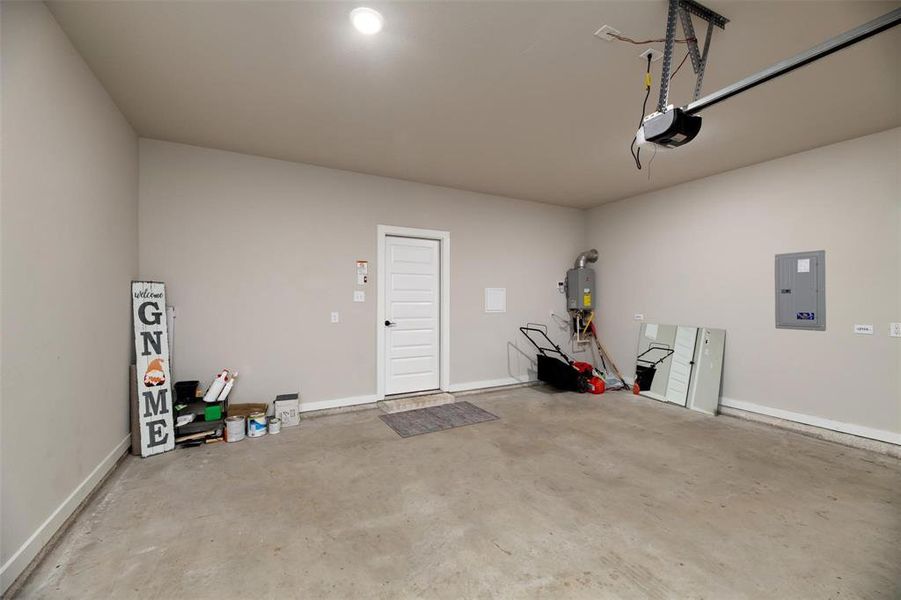 Garage with electric panel, tankless water heater, and a garage door opener Garage with electric panel, tankless water heater, and a garage door opener