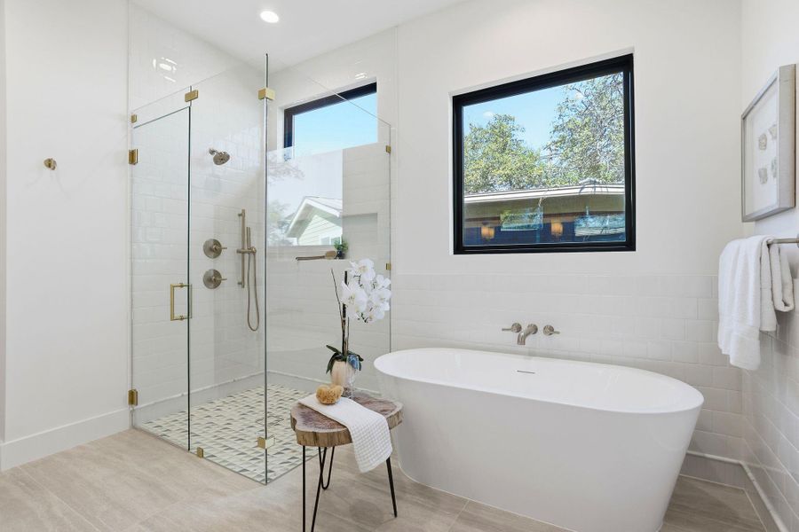 Bathroom featuring a soaking tub, a stall shower, tile walls, and wainscoting