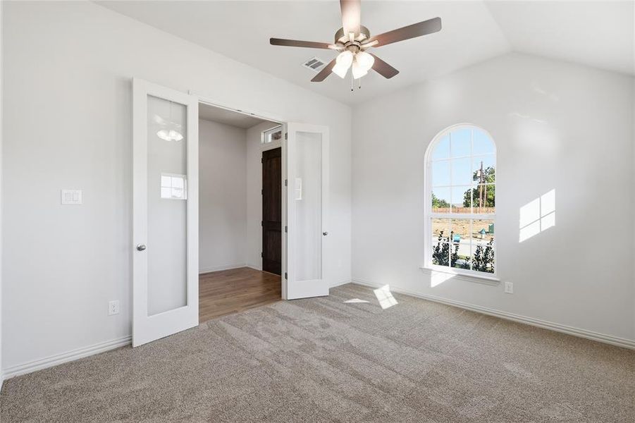 Empty room featuring a ceiling fan, light carpet, and lofted ceiling Empty room featuring a ceiling fan, light carpet, and lofted ceiling
