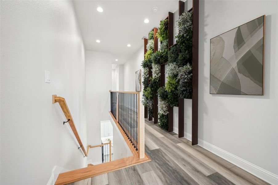 Upstairs virtually staged hallway with light hardwood staircase and LVP flooring.