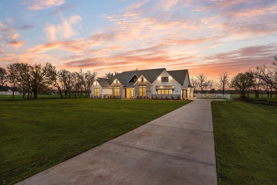 View of front of house featuring stone siding, a front yard, and driveway