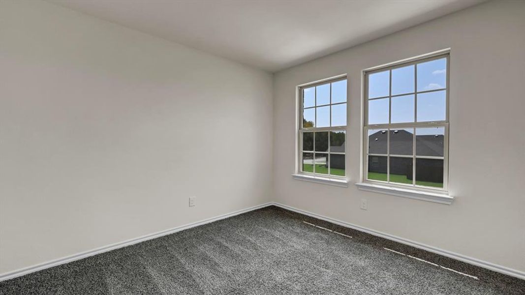 Interior room featuring two vertical windows with grid inserts and white trim, neutral white walls, and gray textured carpeting