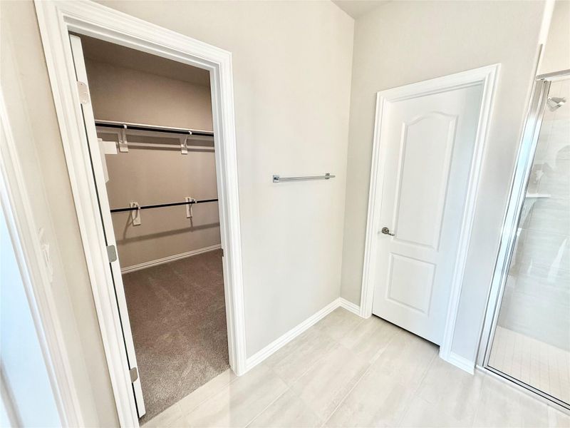 Bathroom with a shower stall, a spacious closet, light carpet, and light tile patterned floors Bathroom with a shower stall, a spacious closet, light carpet, and light tile patterned floors