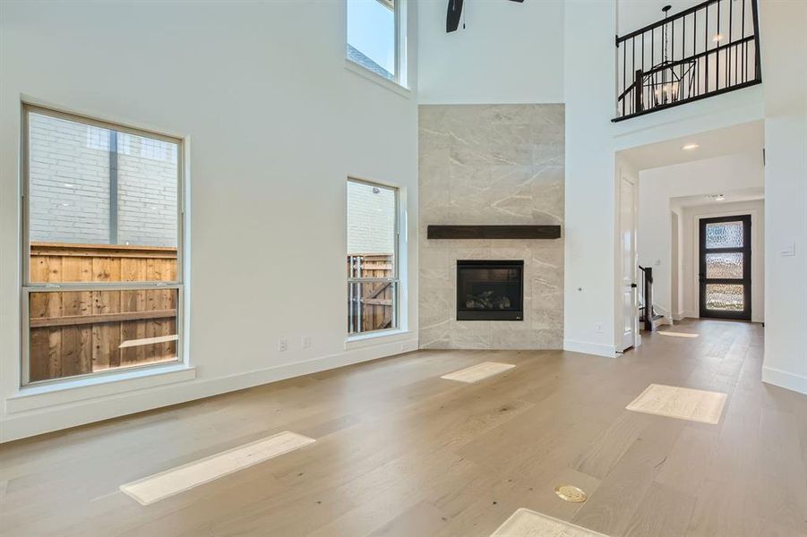 Unfurnished living room with a high ceiling, a wealth of natural light, a tile fireplace, and hardwood / wood-style flooring