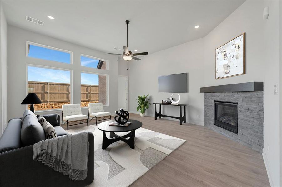 Living area featuring a ceiling fan, light wood finished floors, a stone fireplace, and recessed lighting