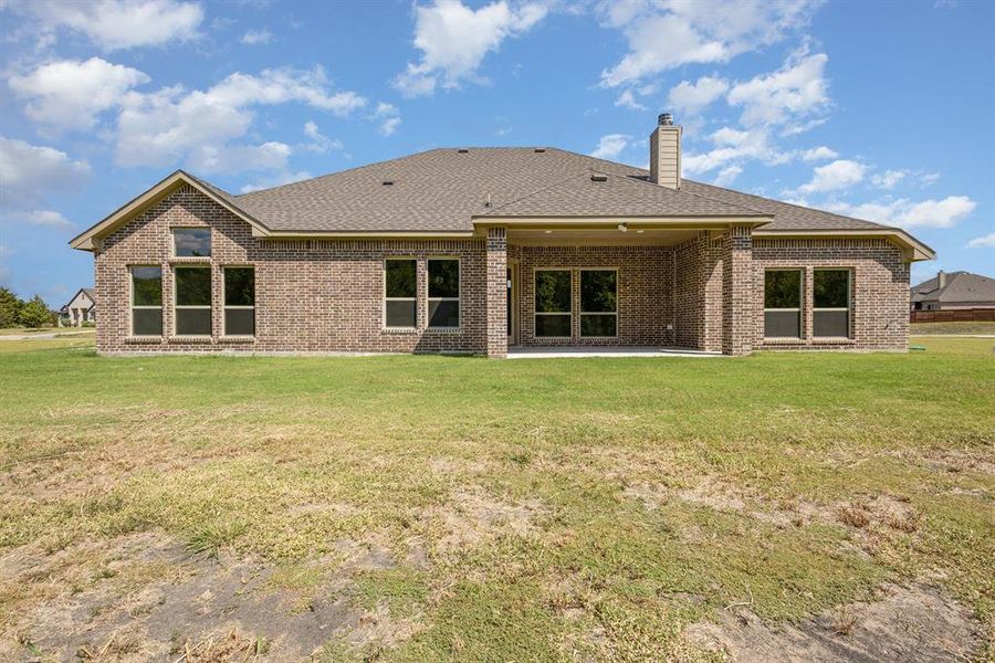 Back of house with a patio area, a lawn, roof with shingles, and brick siding Back of house with a patio area, a lawn, roof with shingles, and brick siding
