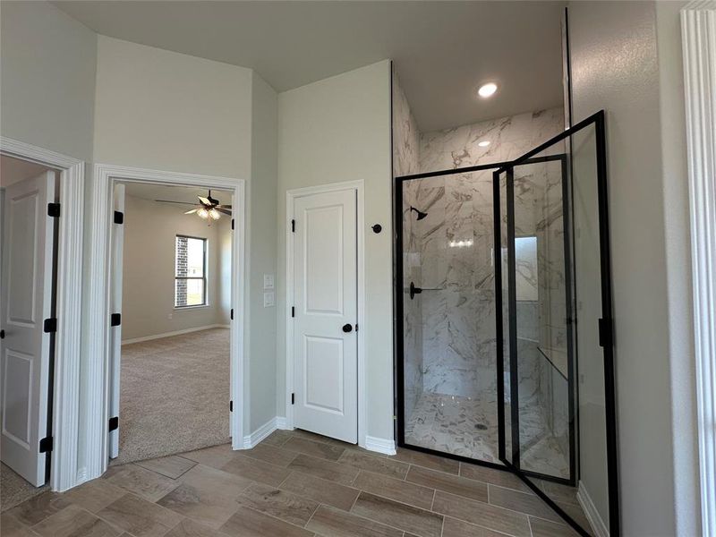 Bathroom with a marble finish shower and ceiling fan