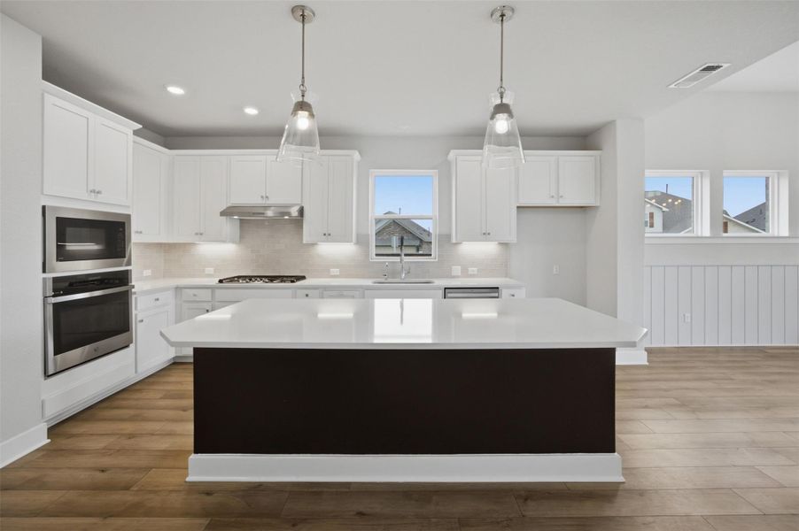 Prepare meals in a kitchen featuring an expansive island, abundant cabinetry, and durable flooring.