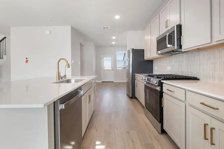Kitchen featuring stainless steel appliances, light wood finished floors, a kitchen island with sink, white cabinets, and recessed lighting