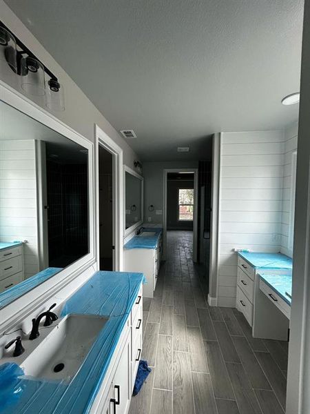 Full bathroom with a textured ceiling, vanity, visible vents, and wood tiled floor