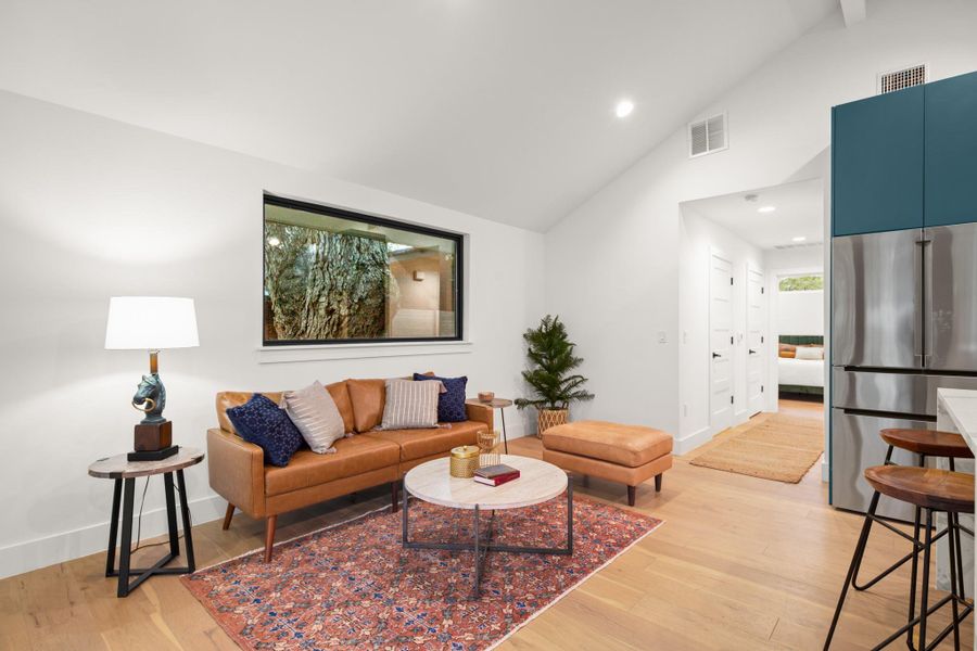 Living area with light wood-type flooring, high vaulted ceiling, and recessed lighting