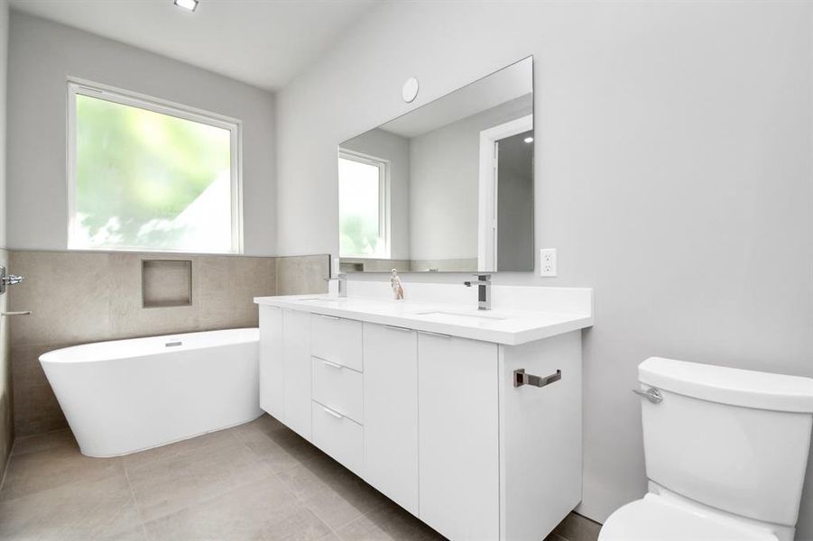 Modern Primary bath with soaking tub and big windows to see the greenery outside.