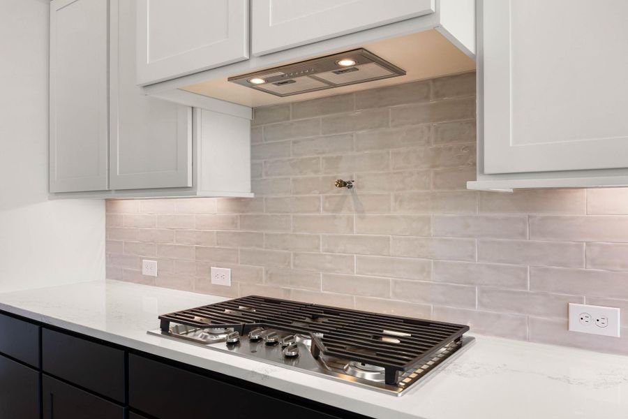 Close-up of the gourmet cooking station, emphasizing premium built-in features and custom finishes. A high-end stainless steel 5-burner gas cooktop is seamlessly integrated into the pristine white quartz countertops, accented by a convenient pot filler faucet centered on the wall. Close-up of the gourmet cooking station, emphasizing premium built-in features and custom finishes. A high-end stainless steel 5-burner gas cooktop is seamlessly integrated into the pristine white quartz countertops, accented by a convenient pot filler faucet centered on the wall.